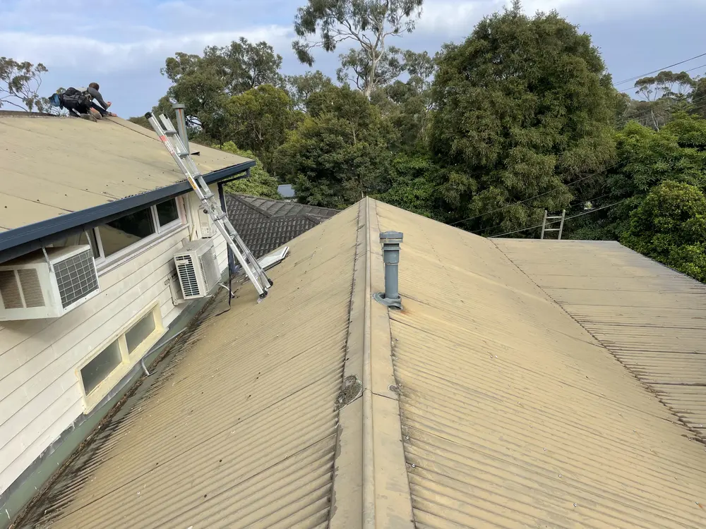 Old faded metal roof on a weatherboard home before replacement