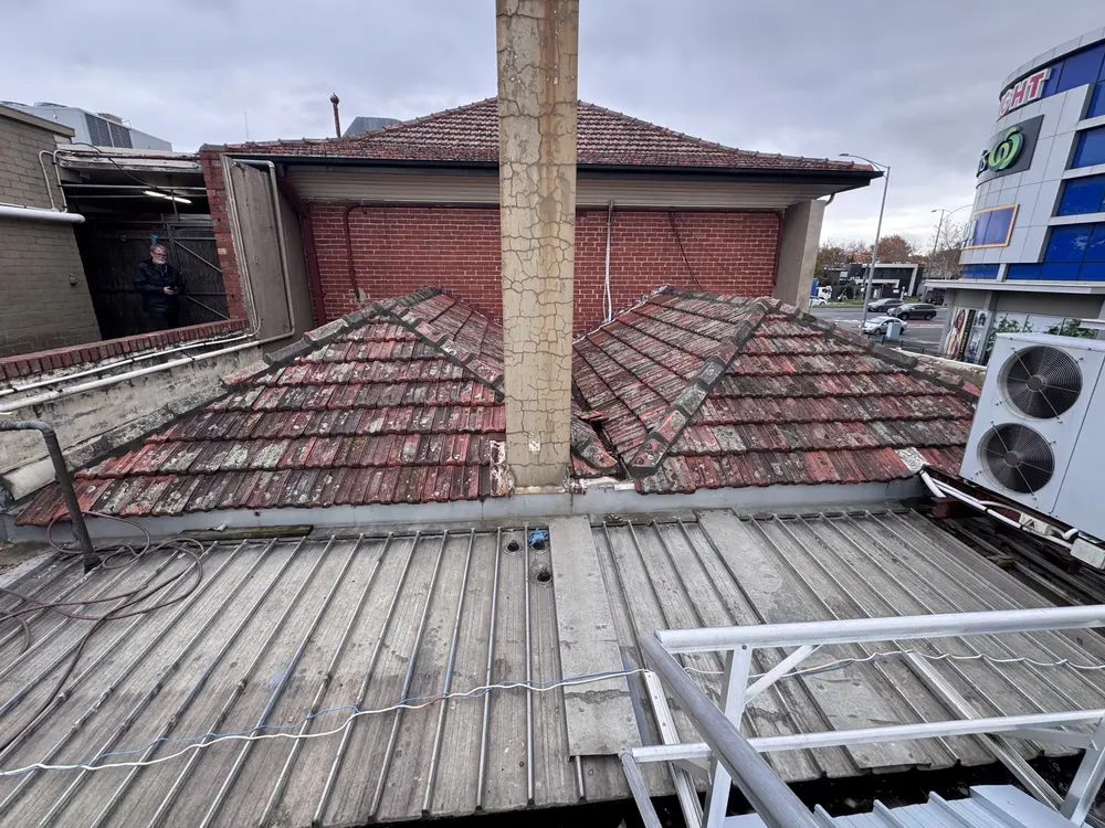 Worn terracotta tile roof on a shopfront before replacement
