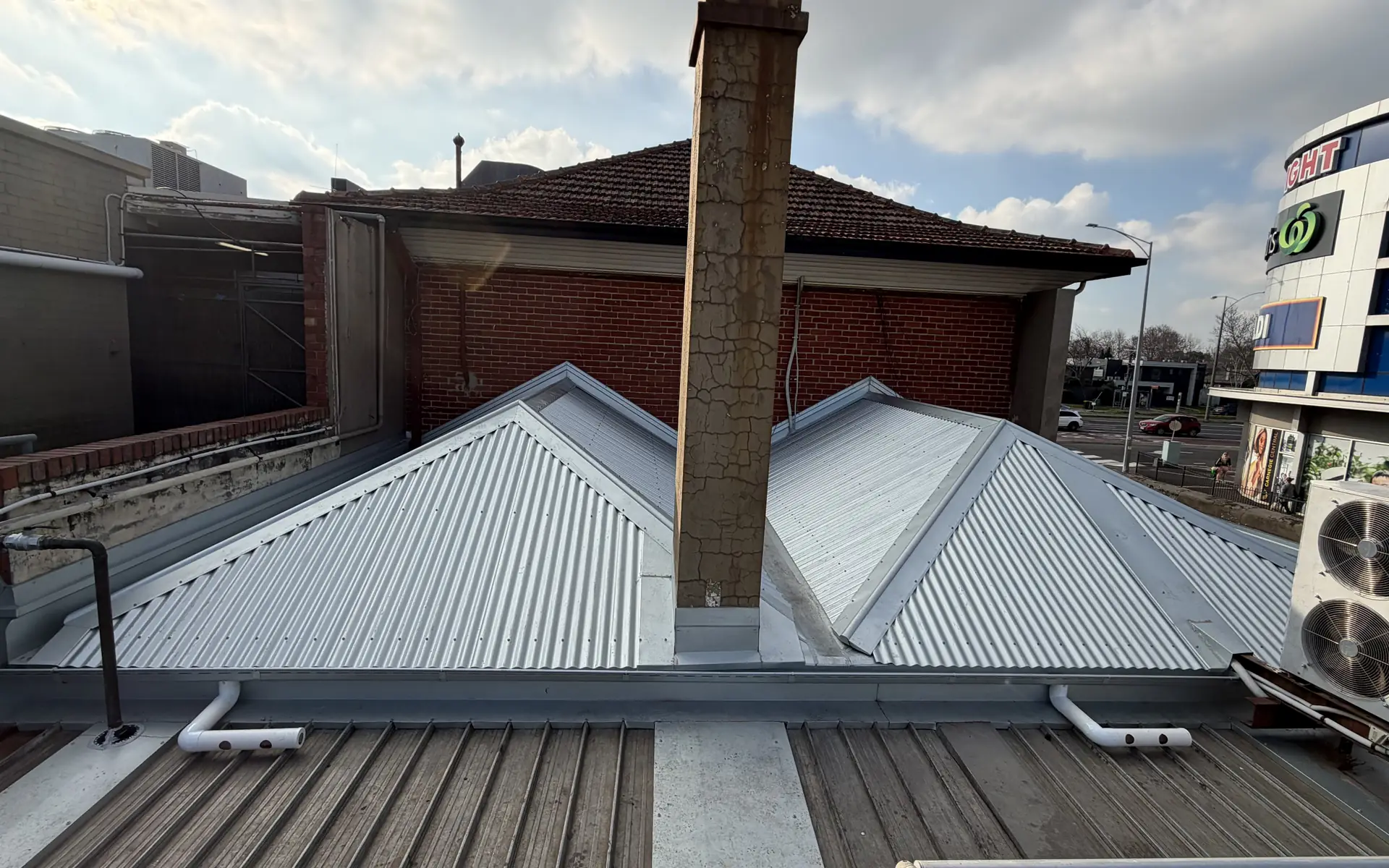 Repaired metal roof sections around a chimney on a Melbourne building
